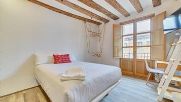 Ein Schlafzimmer mit einem Bett, einem Holzstuhl, einem Schreibtisch und einem Fenster mit Blick.