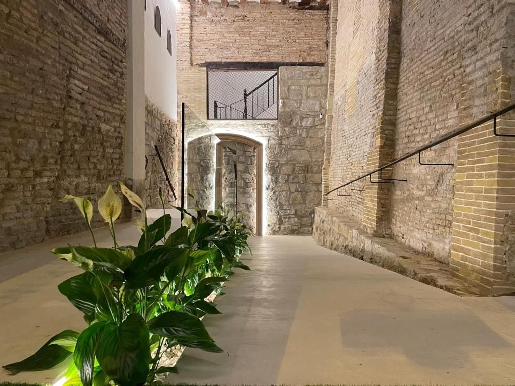 A corridor with brick walls, a concrete floor, and a staircase leading to an upper level.