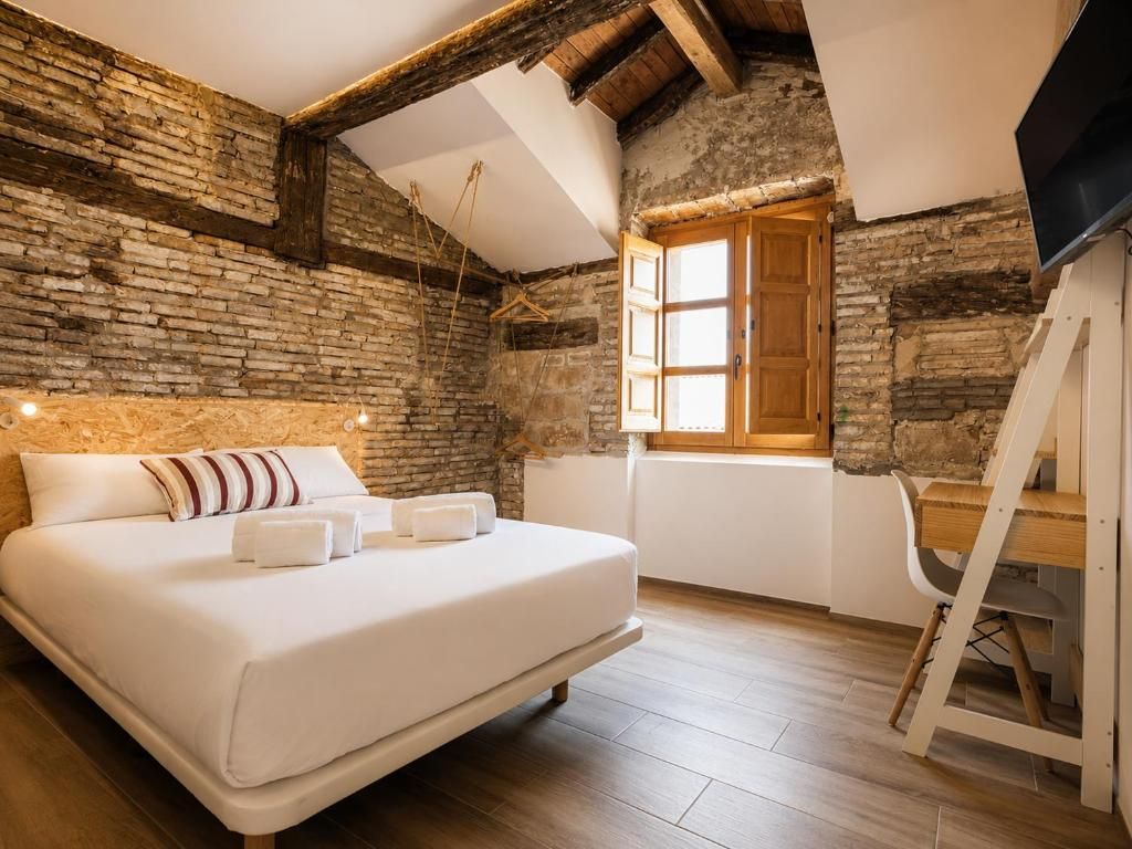 Un dormitori amb un llit, un escriptori de fusta, una televisió i una finestra amb vista a l'exterior.
