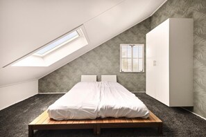 A bedroom with a sloped ceiling, a skylight, a bed, a wardrobe, and a window with shutters. - Luxurious home behind the dunes of Julianadorp (Julianadorp)