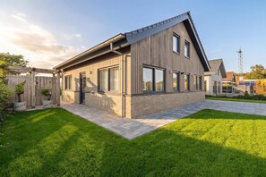 A modern two-story house with a sloped roof, large windows, and a well-maintained lawn. - Luxurious home behind the dunes of Julianadorp (Julianadorp)