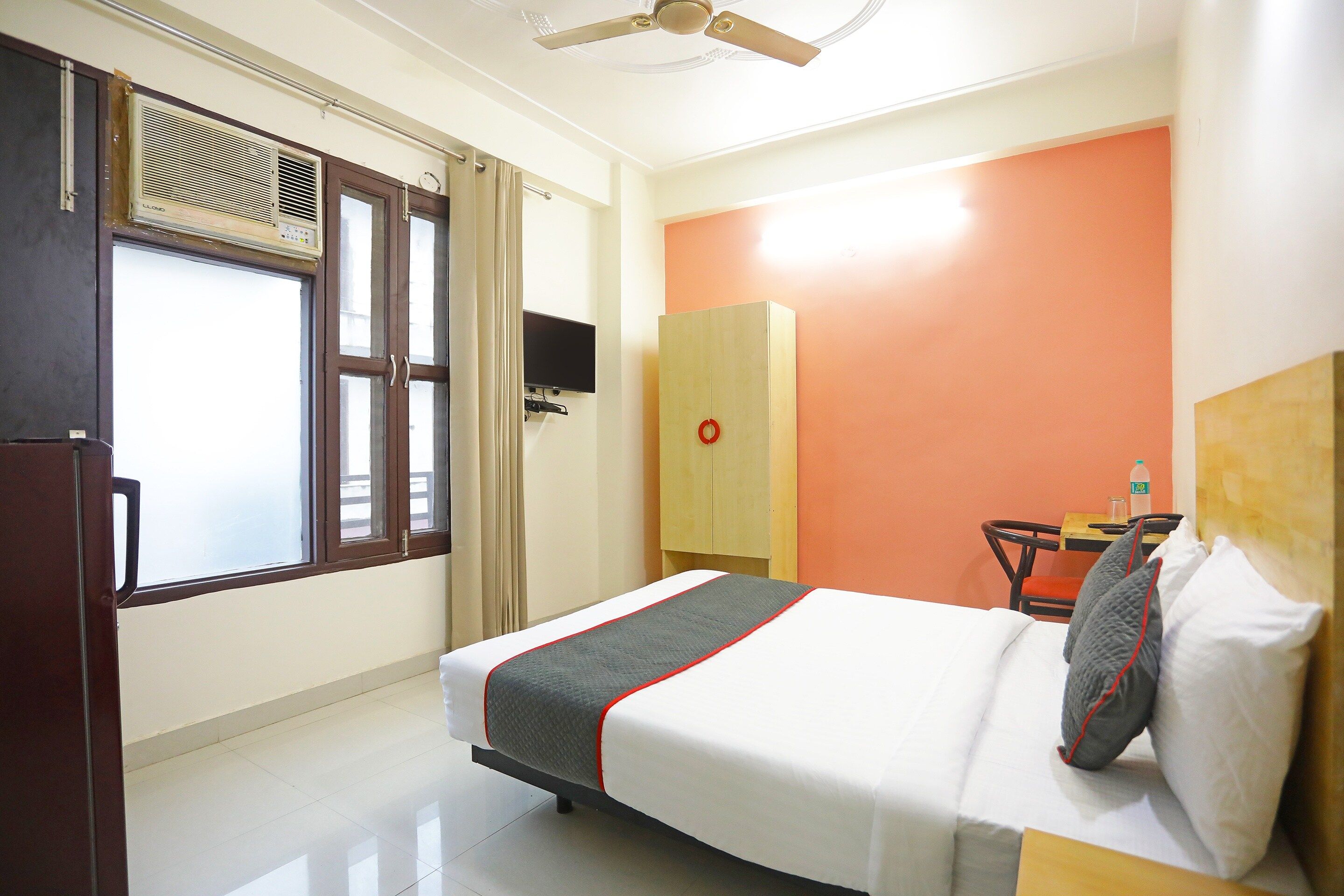 Une chambre d’hôtel équipée d’un lit, d’un bureau, d’une chaise, d’une armoire et d’une fenêtre avec des stores.