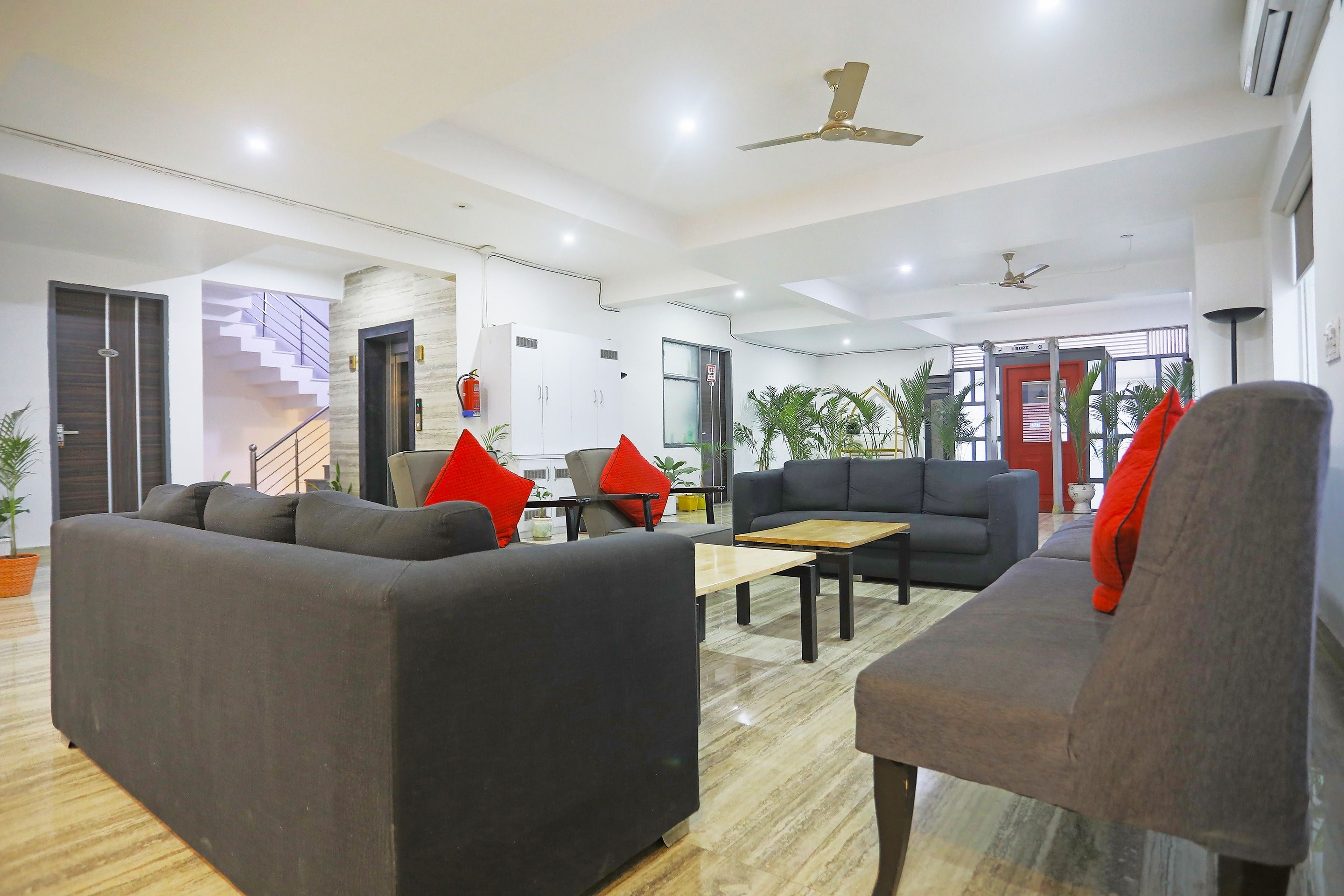 Un moderno vestíbulo de hotel con un mostrador de recepción, zona de estar con sofás y sillones, una escalera y un ventanal con vistas.