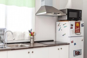 A kitchen with a stainless steel sink, a microwave, and a refrigerator with decorative magnets. - Apartment Near Las Cavellinas Beach (LA OLIVA FUERTEVENTURA)