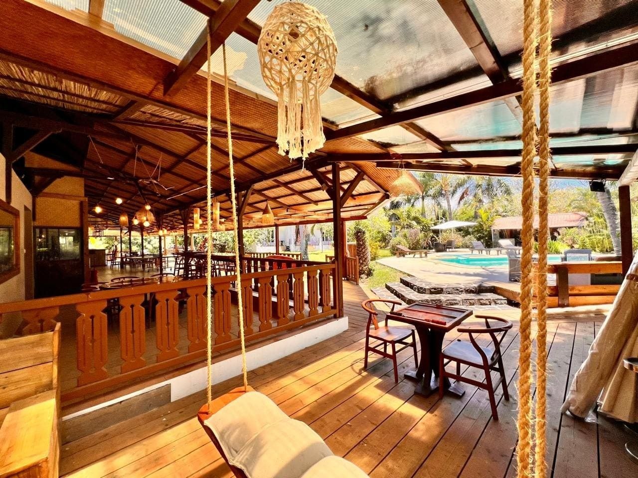Une terrasse extérieure en bois avec une piscine, des meubles en bois et un luminaire suspendu.