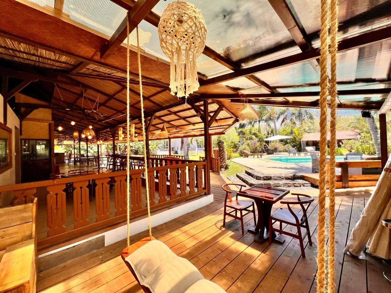 Una terrazza esterna in legno con piscina, mobili in legno e un lampadario.