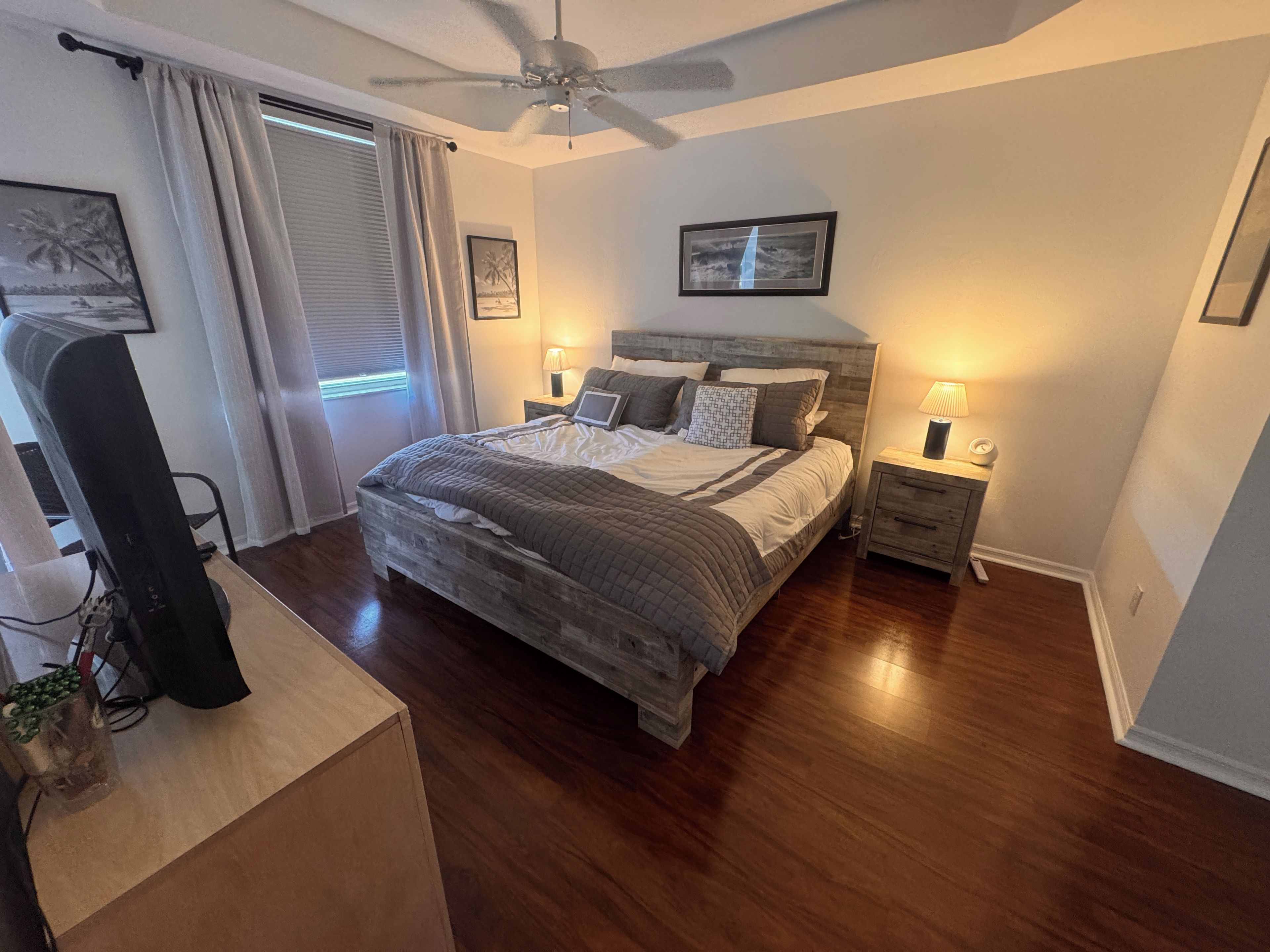 A bedroom with a bed, bedside tables, a ceiling fan, and a window with curtains.
