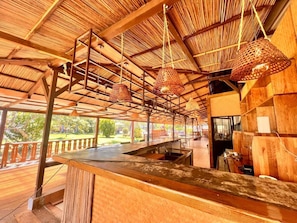 An outdoor bar area with a wooden ceiling and hanging baskets. - Bazaar Square Lodges - Frangipane (Garden) (Grand Baie)
