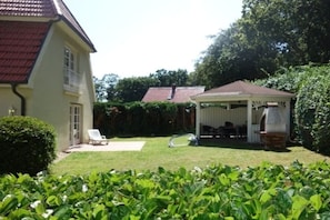Ein Haus mit überdachter Terrasse, Grill und gepflegtem Rasen.
