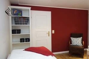 Ein Schlafzimmer mit einem Bett, einem Kleiderschrank, einem Stuhl und einer Tür.