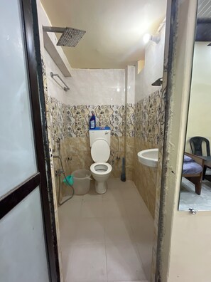 A small bathroom with a toilet, sink, shower, and tiled walls. - 5-bedroom bed & breakfast in brilliant Varanasi with AC (Varanasi)