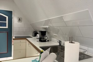 A compact kitchen with a coffee maker, a sink, and a paper towel holder. - "Reetstübchen" - House Shell (Nieblum)