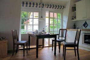 Eine Küche mit Holzausstattung, einem Esstisch mit Stühlen und einem Fenster mit Blick ins Grüne.
