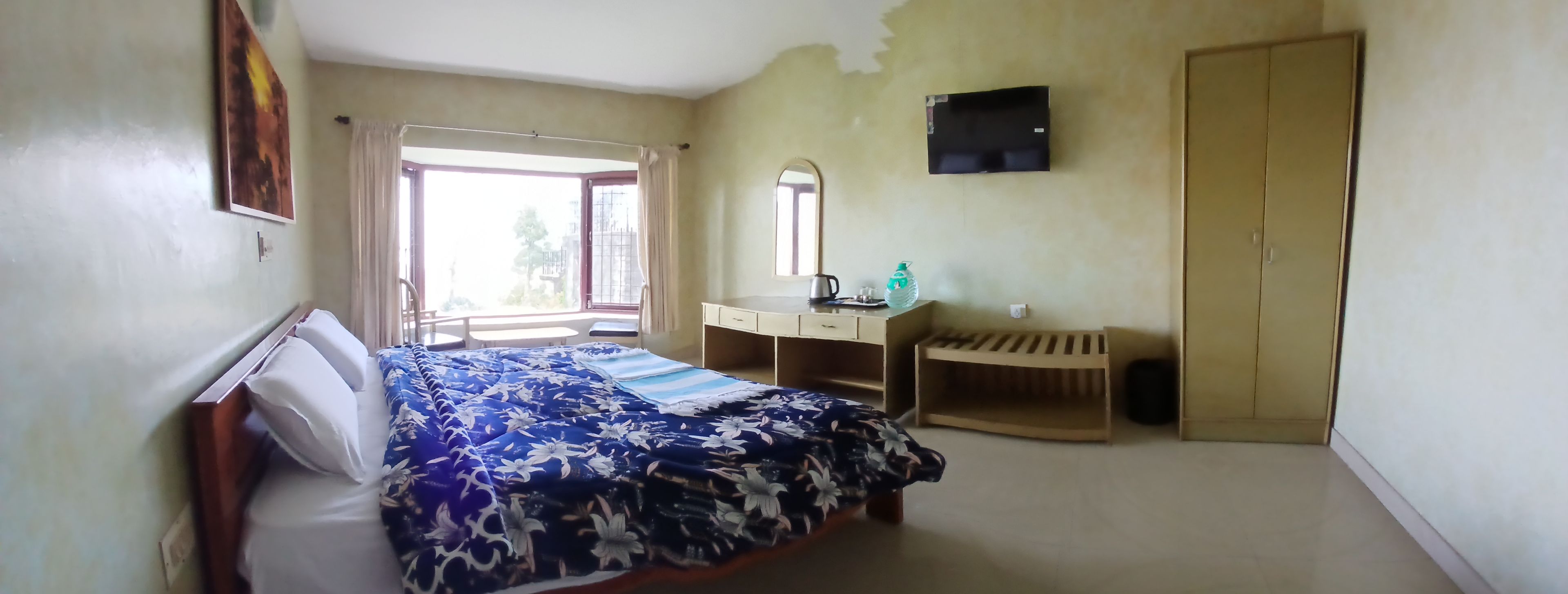 Un dormitorio con cama, escritorio, armario, espejo y ventana.