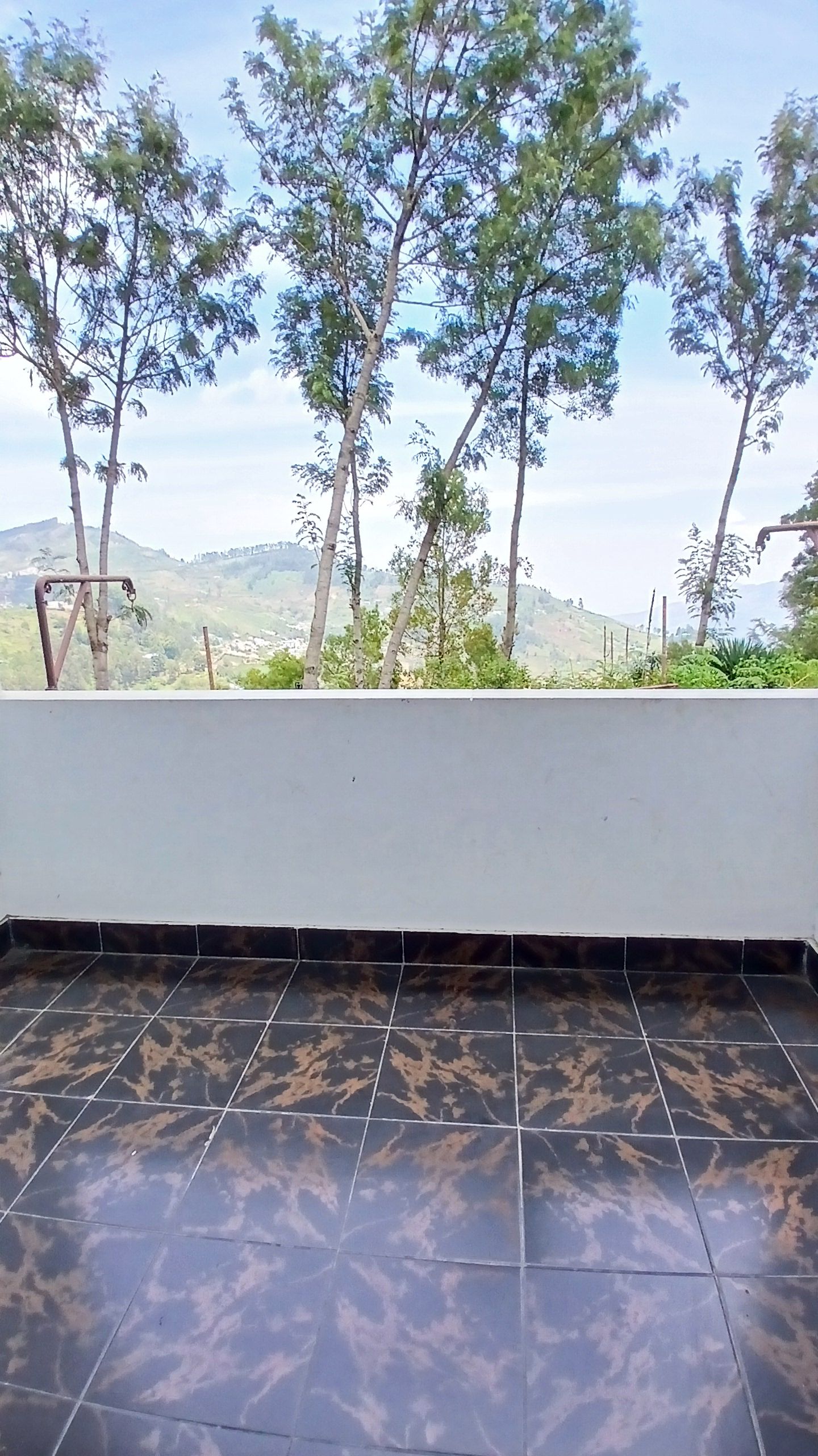 A tiled floor with a view of trees and hills in the background.