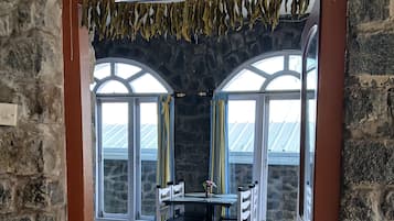 L’entrée d’un restaurant, avec un mur en pierre, une enseigne et une salle à manger comprenant des tables et des chaises.