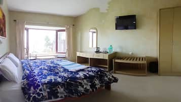 Une chambre à coucher avec un lit, un bureau, une armoire, un miroir et une fenêtre.