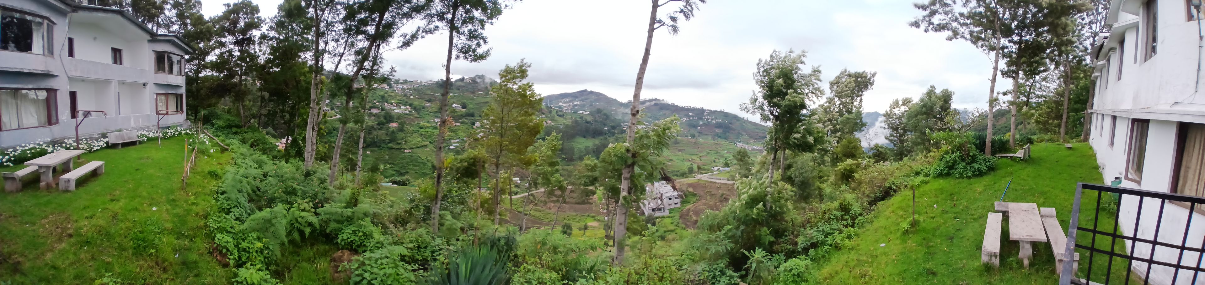 Zona residencial con vista a un valle, rodeada de vegetación y algunos edificios.