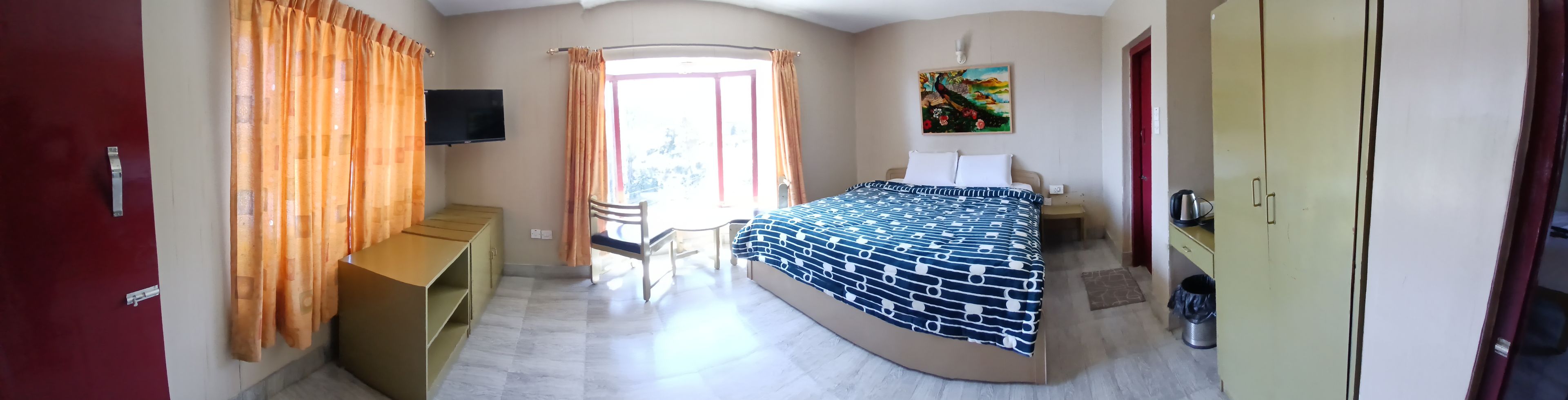 A bedroom with a bed, a desk, a chair, a TV, and a painting on the wall.