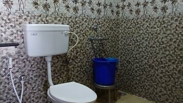A bathroom with a toilet, a blue basin, and a shower.