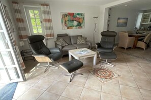 Ein Wohnzimmer mit einer Couch, zwei Sesseln, einem Couchtisch und einem gemusterten Teppich.
