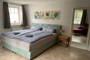 Ein Schlafzimmer mit einem Bett, einem Nachttisch, einem Spiegel und Kunstwerken an der Wand.