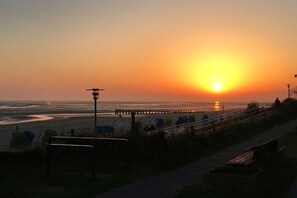 A sunset over a beach with a pier, benches, and a walkway. - "Haus Parkstrasse" - Apt. 01 (Wyk auf Föhr)