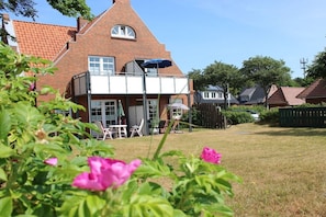 A brick house with a balcony, a lawn, and a fence. - "Haus Parkstrasse" - Apt. 01 (Wyk auf Föhr)