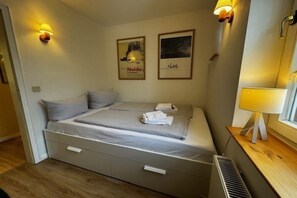Ein Hotelzimmer mit einem Bett, zwei Wandleuchten, einem gerahmten Bild und einem Fenster mit einer Lampe auf dem Nachttisch.