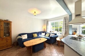 A living room with a sofa, a wooden coffee table, a cabinet, and a kitchen area with a window. - "Oldsum 2, House 94" (Oldsum)