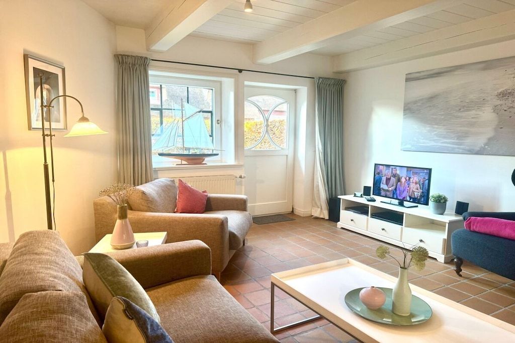 A living room with a sofa, a coffee table, a TV, and a window with curtains.