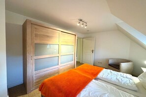 A bedroom with a bed, a wardrobe, and a chair. - Holiday apartment with 1 bedroom (Borgsum)