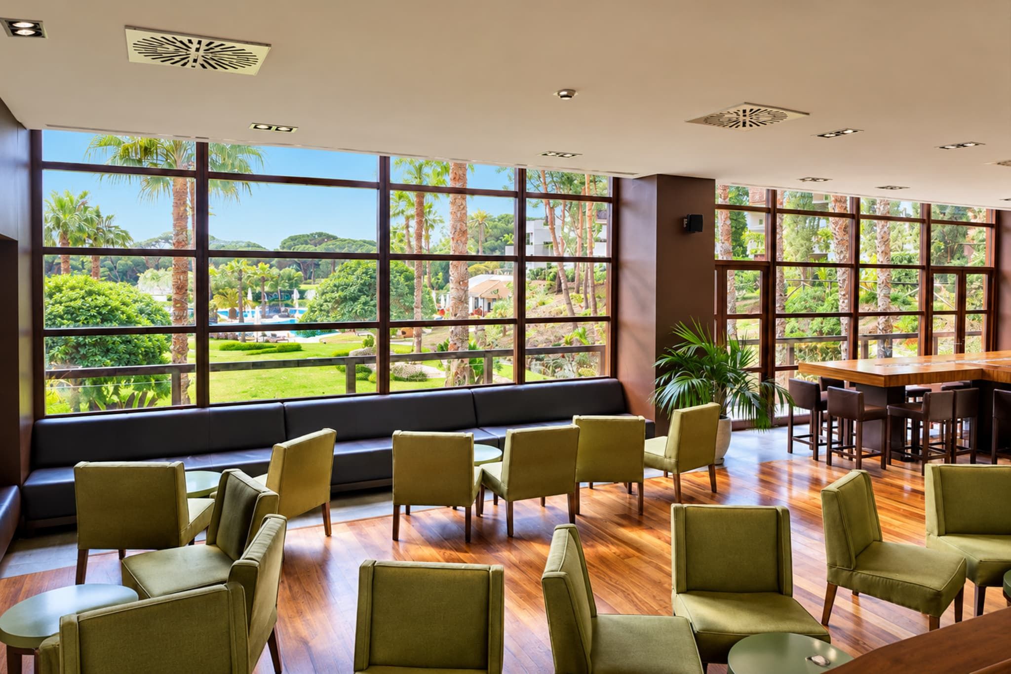 Amplia habitación con ventanas grandes que ofrecen vista a un exuberante jardín y piscina.