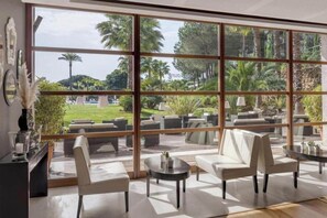 Un área de estar moderna con amplios ventanales, asientos cómodos y vistas a un jardín ajardinado.