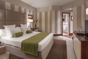 A hotel room with a large bed, bedside tables, a desk, and a bathroom visible through an open door.