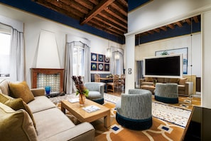 Ein modernes Wohnzimmer mit einer Couch, Sesseln, einem Couchtisch und einem Fernseher.