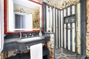 Une salle de bain avec un grand miroir, un lavabo, une douche et un porte-serviettes.