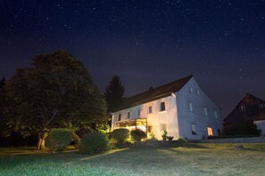 A house with a sloped roof, a porch, and a well-maintained lawn. - Holiday home with 2 bedrooms (Bischofsgrün)