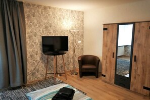 A room with a bed, a television on a stand, a chair, and a wardrobe. - Alice's Holiday Apartment 2 (Arnstadt)