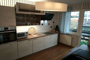 Eine moderne Küche mit Mikrowelle, Backofen und einem großen Fenster mit Vorhängen.