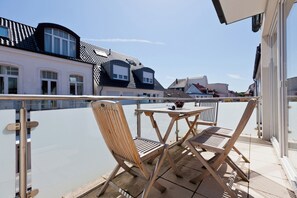 Ein Balkon mit Tisch und zwei Stühlen, mit Blick auf ein Wohngebiet mit Häusern.