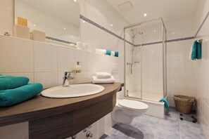 Ein modernes Badezimmer mit einem Holzbadezimmermöbel, einem weißen Waschbecken und einer Duschkabine.