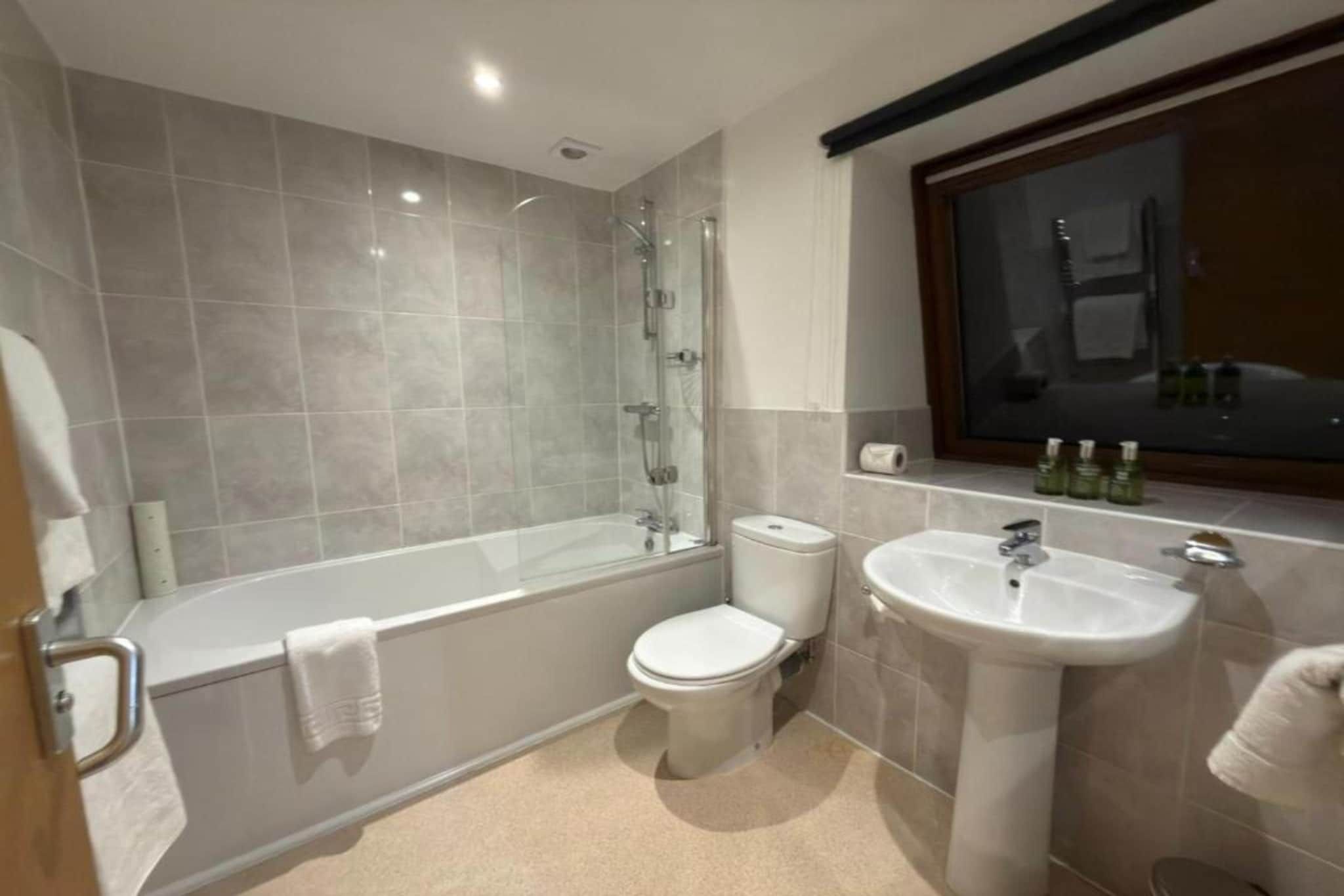 A modern bathroom with a bathtub, toilet, and sink.