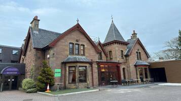 A historic building with a reception area, a small tree, and outdoor seating.