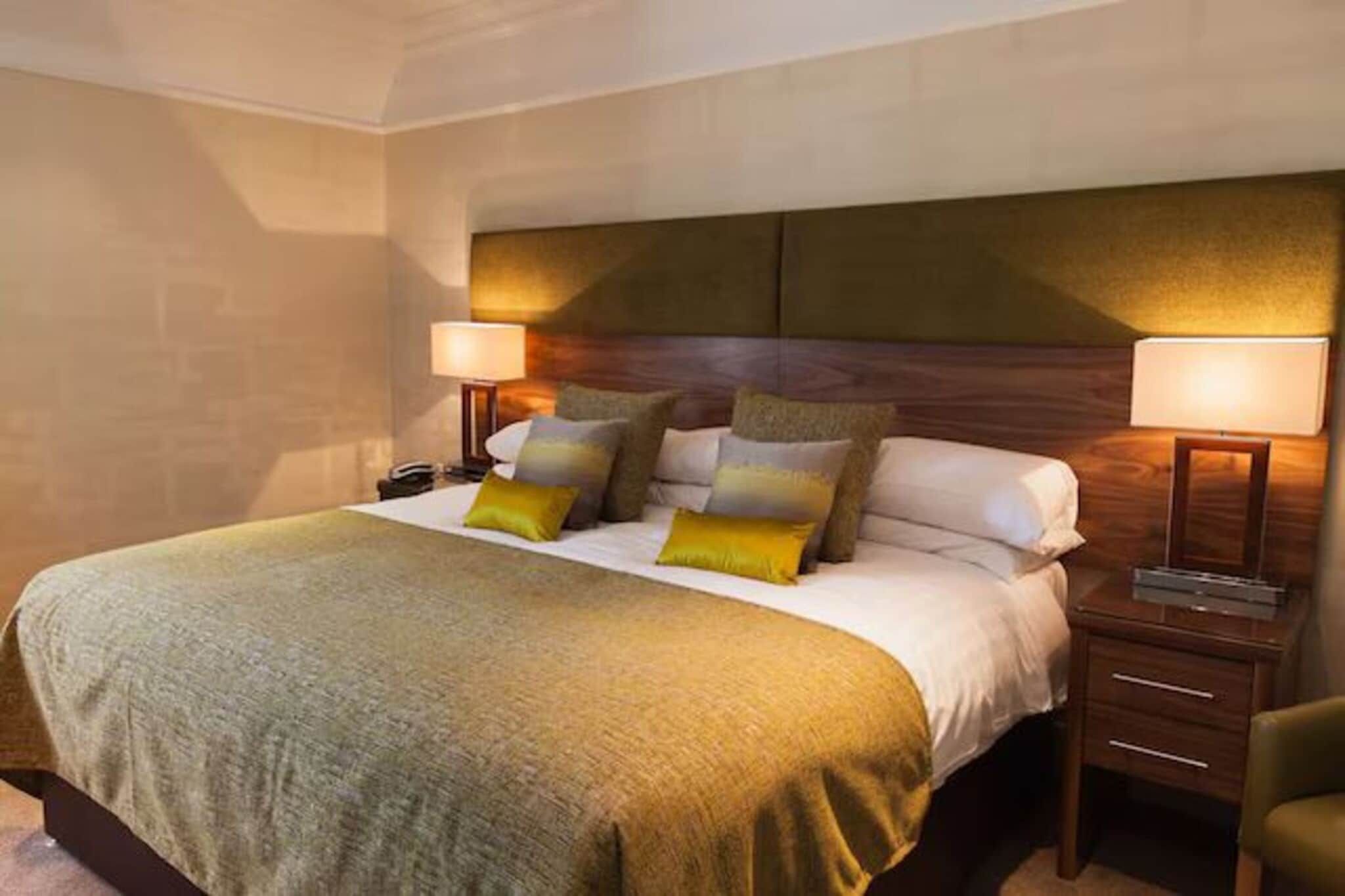 A hotel room with a large bed, two bedside tables, and a headboard.