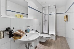 Ein modernes Badezimmer mit Waschbecken, Toilette und Duschkabine aus Glas.