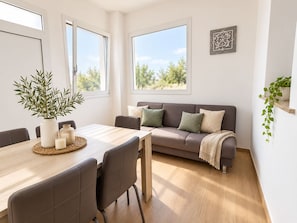 A modern living room with a wooden dining table, grey sofa, and a potted plant. - Levante Privé Pool Retreat Salento (Lequile)