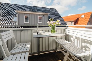 Ein Balkon mit Tisch, zwei Stühlen und einer Blumenvase.