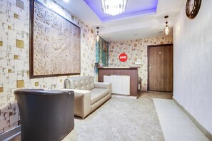 A reception area with a sofa, a trash bin, a reception desk, and a door.