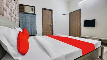 Una habitación de hotel con una cama, un televisor en la pared y una ventana con persianas.